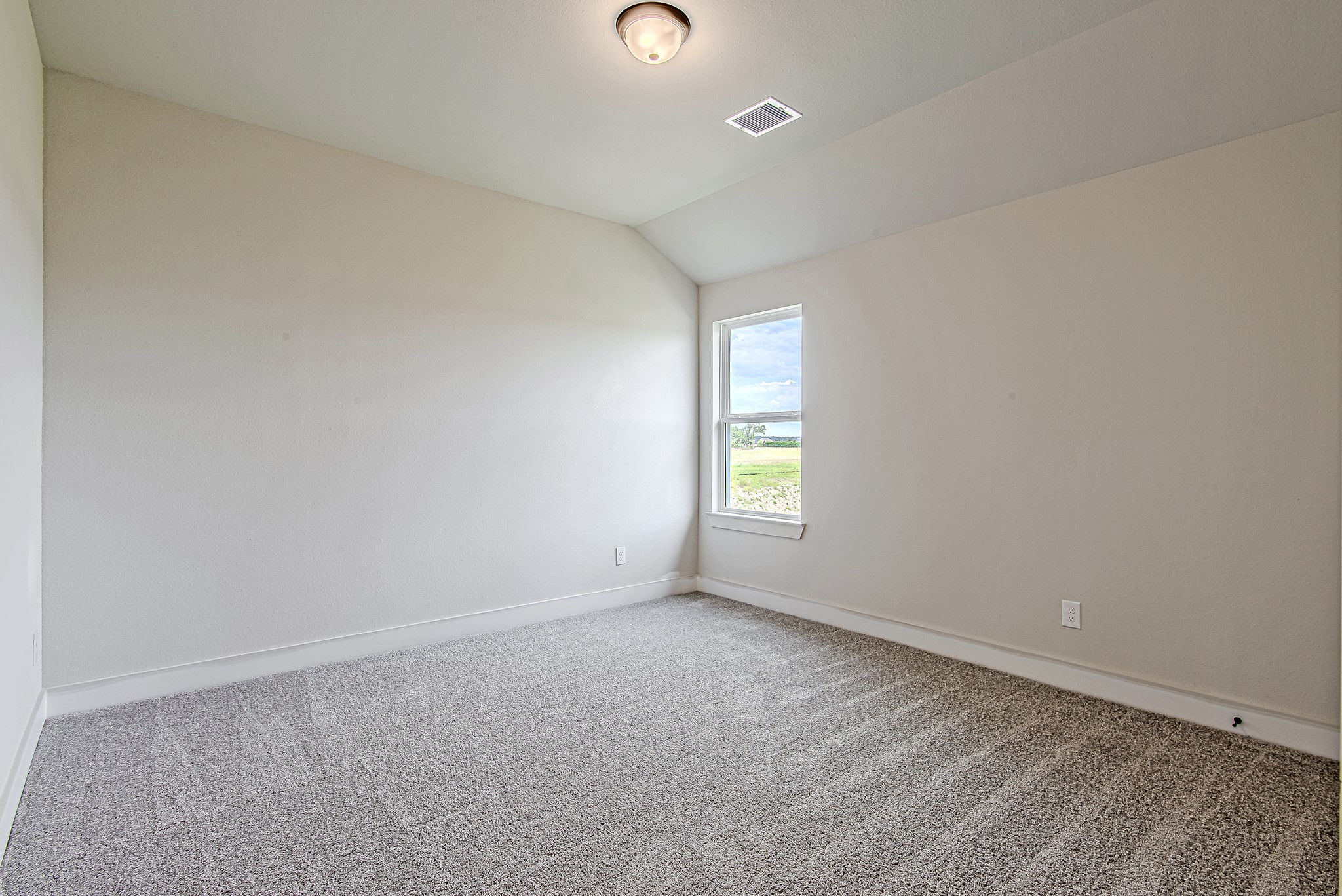 141 Peninsula Point Drive Montgomery, TX 77356 - Photo 38 of 47 Spacious secondary bedroom featuring a vaulted ceiling, fresh carpeting, and serene views of the lush green space beyond.