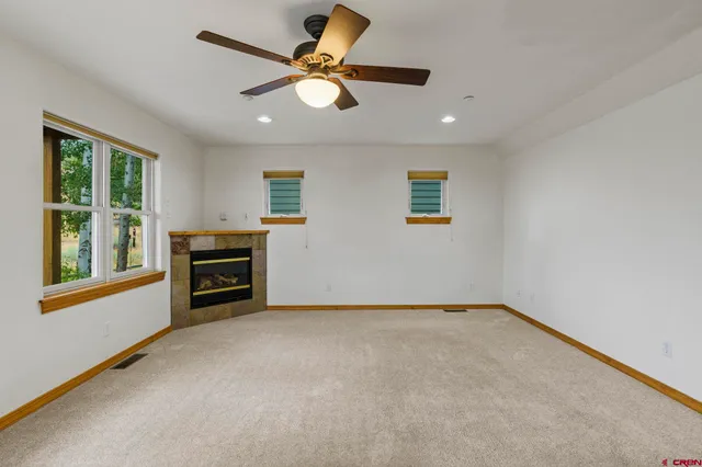 an empty room with windows and ceiling fan