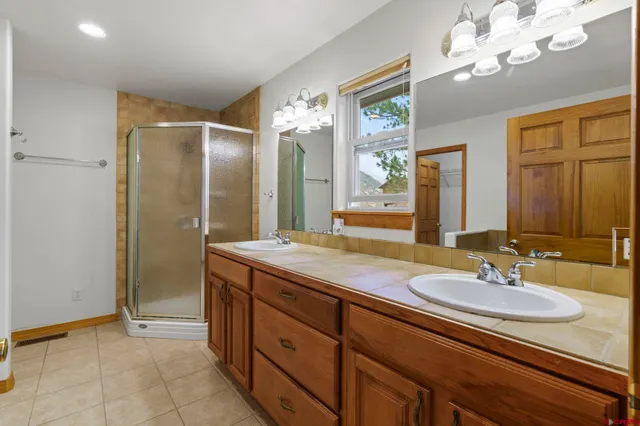 a bathroom with a sink double vanity granite and a shower