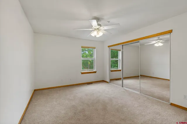 an empty room with windows and fan