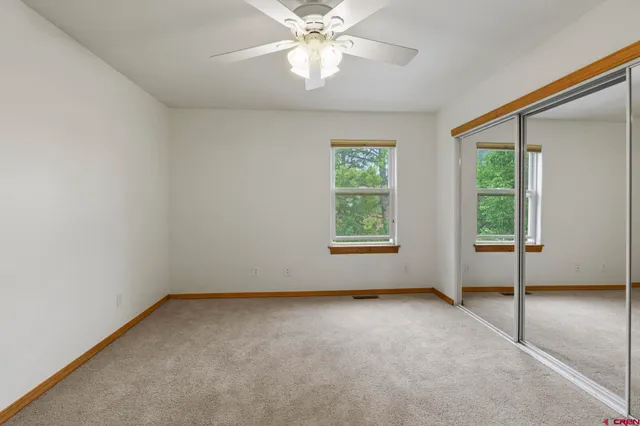 an empty room with windows and fan