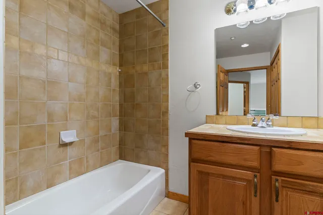 a bathroom with a granite countertop sink a toilet a mirror and bathtub