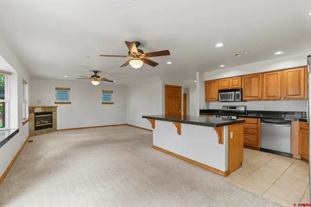 a view of kitchen with stainless steel appliances kitchen island granite countertop a stove top oven a sink a dining table and chairs