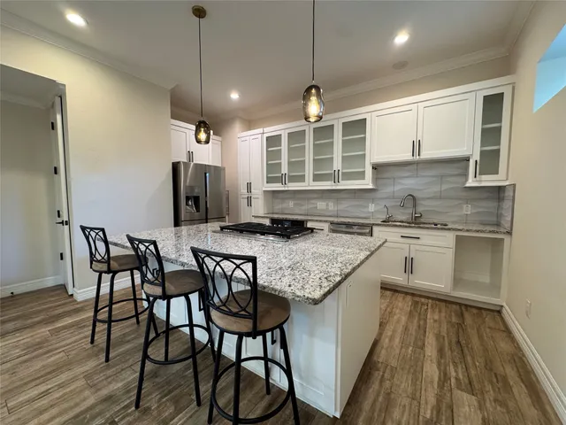 a kitchen with granite countertop kitchen island wooden floor center island and stainless steel appliances