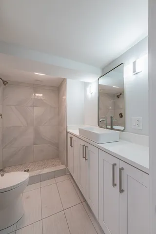 a bathroom with a granite countertop sink a toilet a mirror and shower