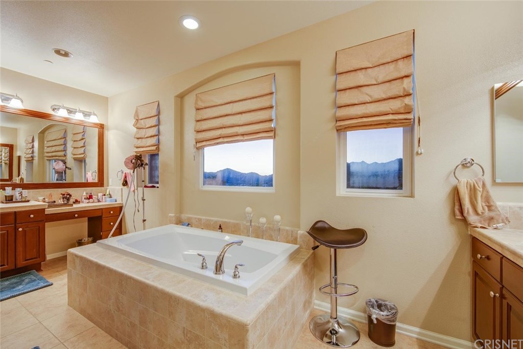 20855 Piazza Way Porter Ranch, CA 91326 - Photo 22 of 38 a spacious bathroom with a tub a sink and a large mirror
