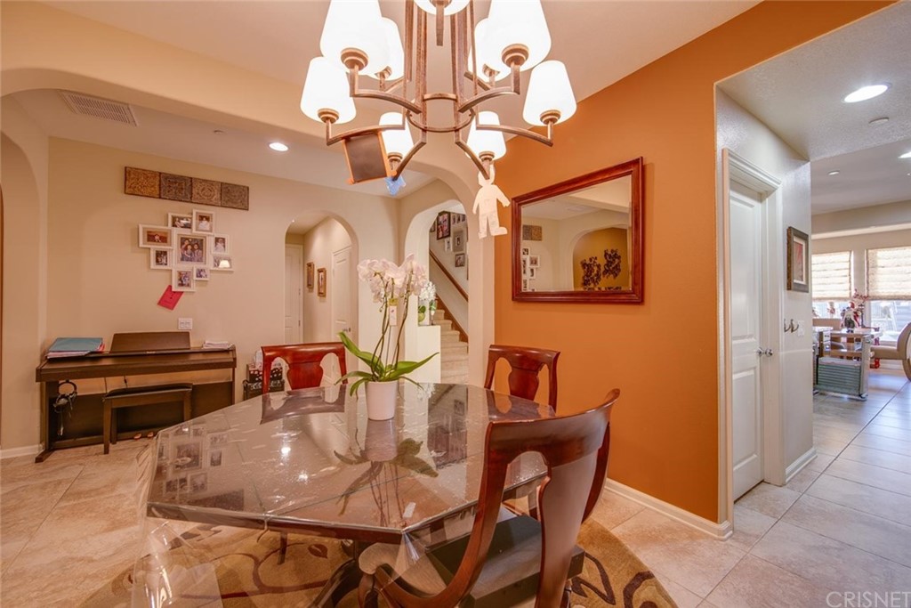 20855 Piazza Way Porter Ranch, CA 91326 - Photo 4 of 38 a dining room with wooden floor a chandelier a wooden table and chairs