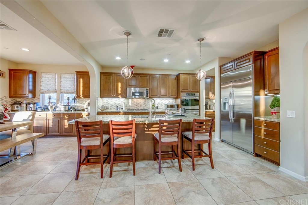 20855 Piazza Way Porter Ranch, CA 91326 - Photo 7 of 38 a kitchen with kitchen island a dining table and chairs