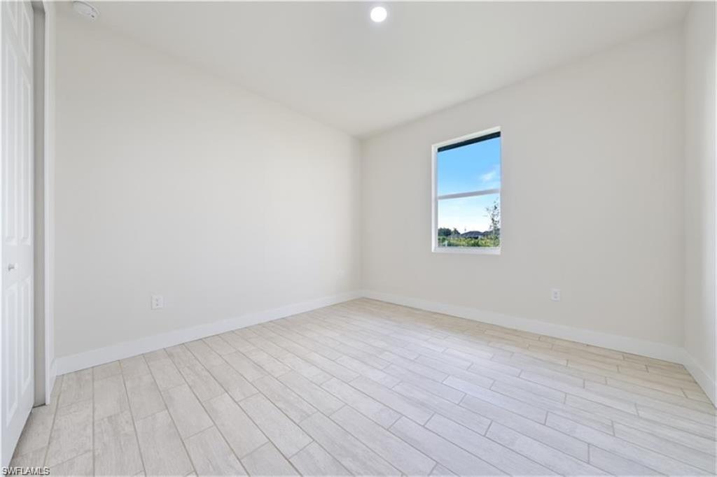 3008 23rd Street Southwest Lehigh Acres, FL 33976 - Photo 7 of 10 an empty room with wooden floor and windows