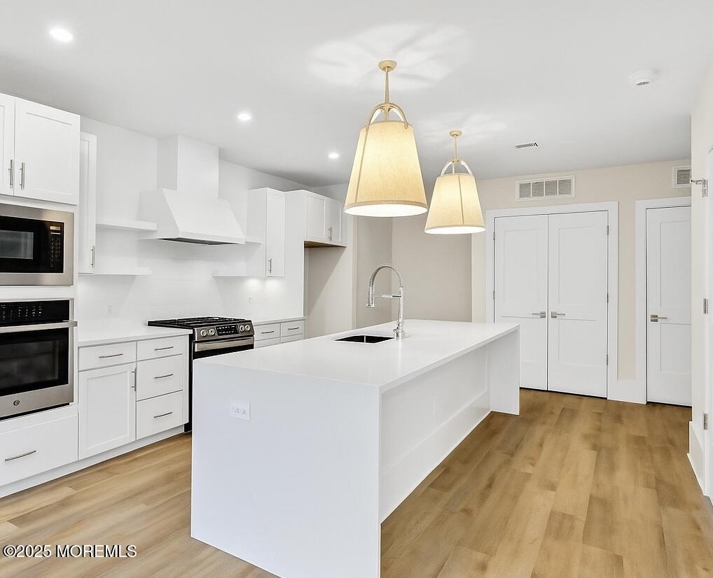 215 2nd Avenue, Unit 106 Asbury Park, NJ 07712 - Photo 8 of 24 a kitchen with kitchen island a stove a sink a center island and wooden floor