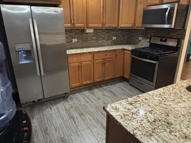 a kitchen with stainless steel appliances granite countertop a refrigerator stove and sink