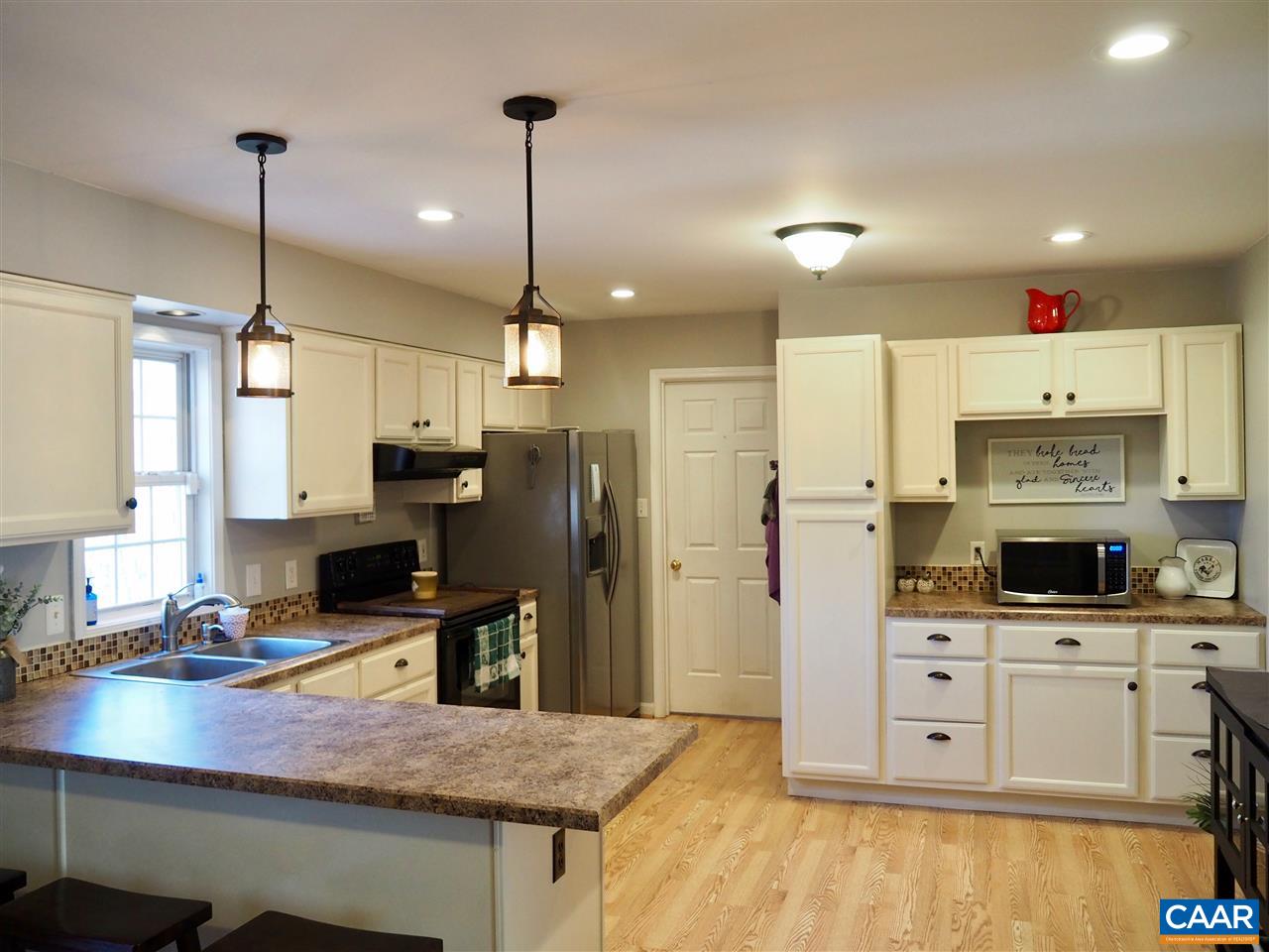 2880 Craigland Road Charlottesville, VA 22902 - Photo 12 of 48 a kitchen with stainless steel appliances kitchen island granite countertop a stove a sink a refrigerator a center island a stove and white cabinets with wooden floor