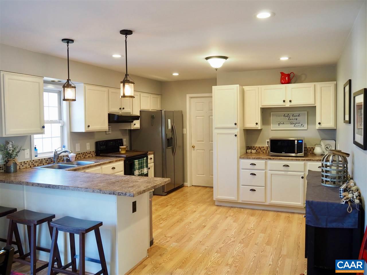 2880 Craigland Road Charlottesville, VA 22902 - Photo 7 of 48 a kitchen with kitchen island a stove a refrigerator a sink a stove and white cabinets with wooden floor