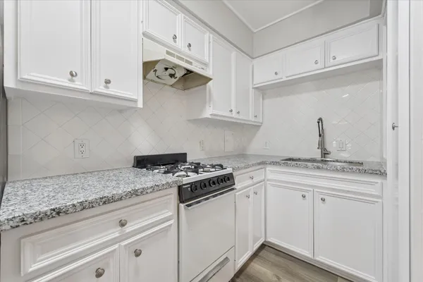 a kitchen with granite countertop white cabinets and a stove
