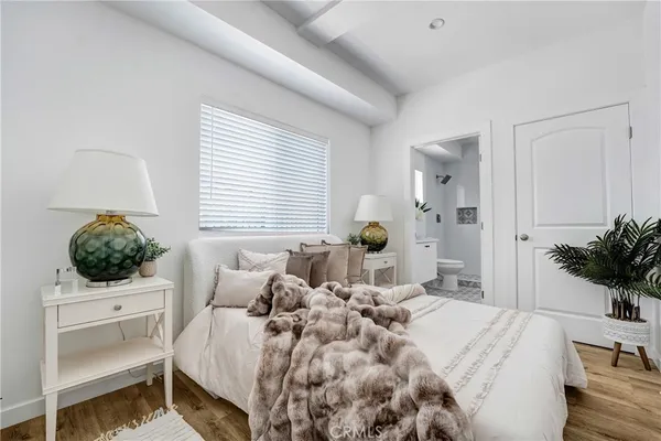 a bedroom with a bed a potted plant and a window