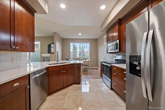 a large kitchen with stainless steel appliances granite countertop a refrigerator a sink dishwasher a oven and a refrigerator