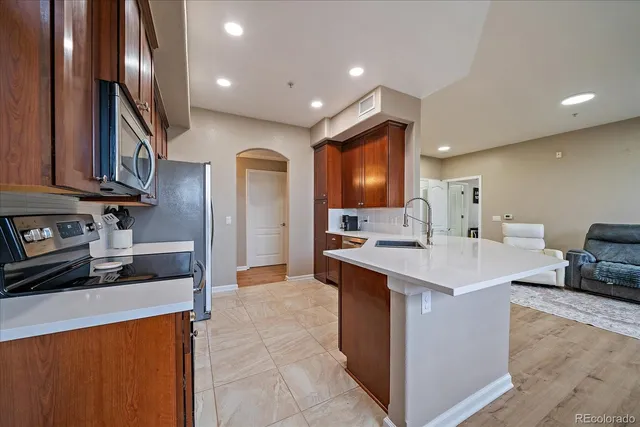 a kitchen with stainless steel appliances kitchen island granite countertop a refrigerator and a sink