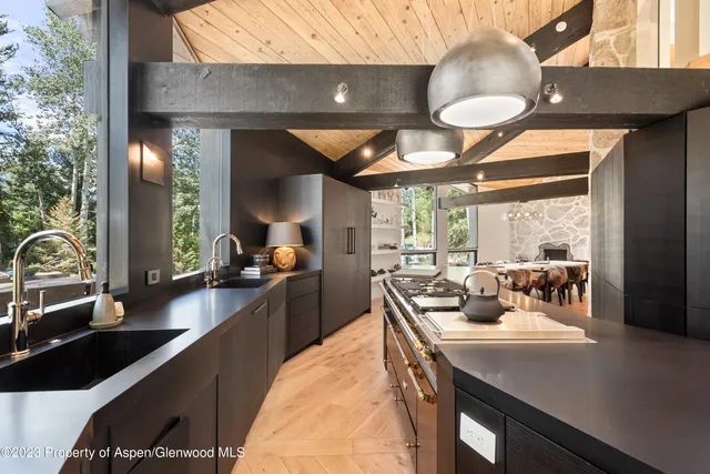 a kitchen with a sink dishwasher a stove and a dining table with wooden floor