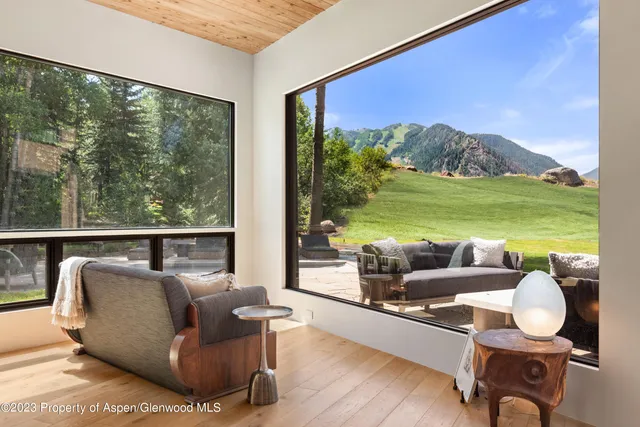 a living room with furniture floor to ceiling window and an outdoor view