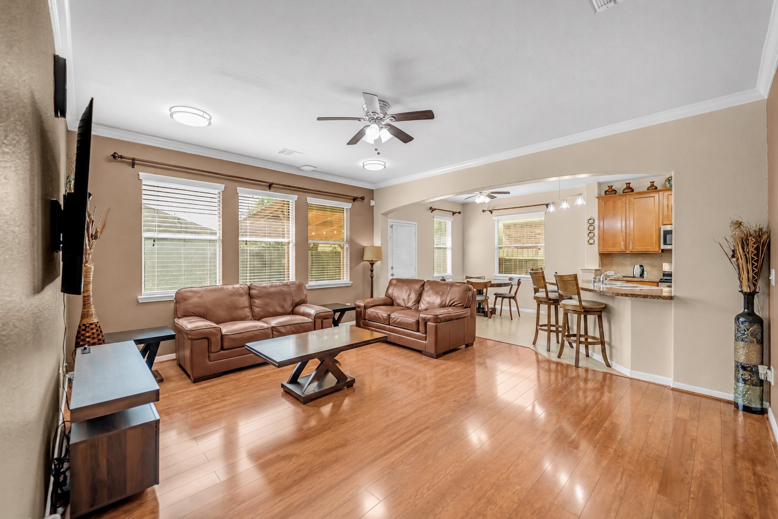 5406 Quarry Ridge Road Richmond, TX 77407 - Photo 10 of 36 Spacious open-concept living room with rich wood flooring, abundant natural light, and seamless flow into the kitchen and breakfast area—creating a warm, inviting space to gather, relax, and entertain.