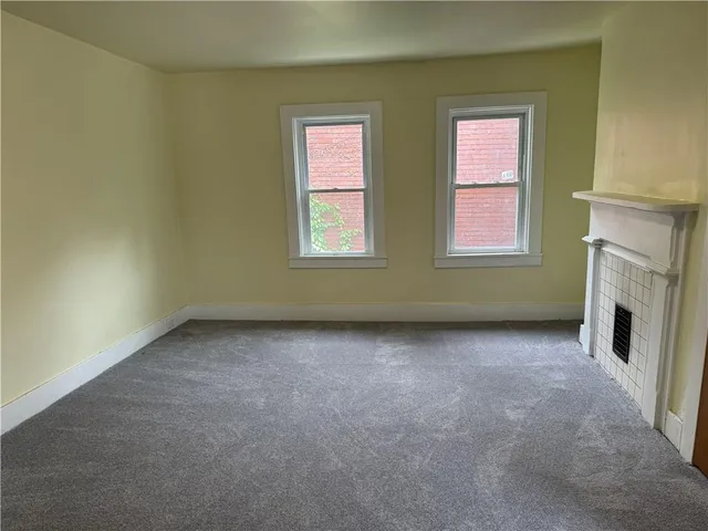 an empty room with windows and fireplace