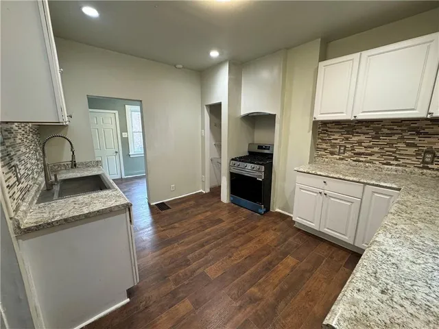 a kitchen with granite countertop a sink stove and refrigerator