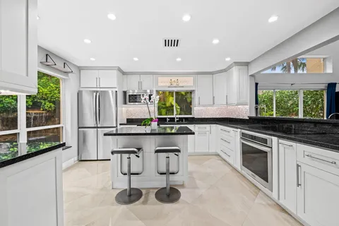 a kitchen with stainless steel appliances granite countertop a sink and a refrigerator