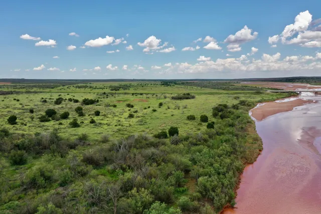 an aerial view of residential house with outdoor space and trees all around