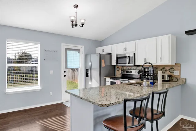 a kitchen with stainless steel appliances granite countertop a stove top oven a refrigerator a sink and a dining table with wooden floor