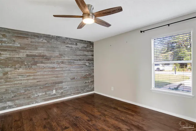 a view of empty room with wooden floor and fan