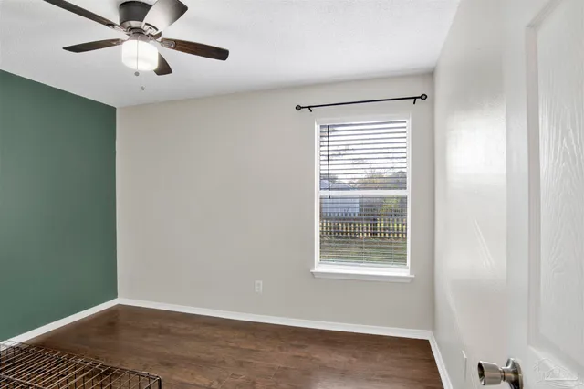 a view of an empty room with chandelier fan and a window