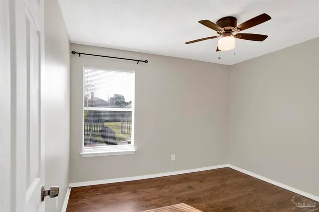 an empty room with a window and a ceiling fan