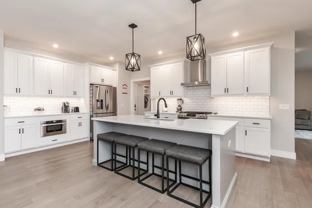 a kitchen with stainless steel appliances granite countertop a sink a stove a refrigerator and white cabinets