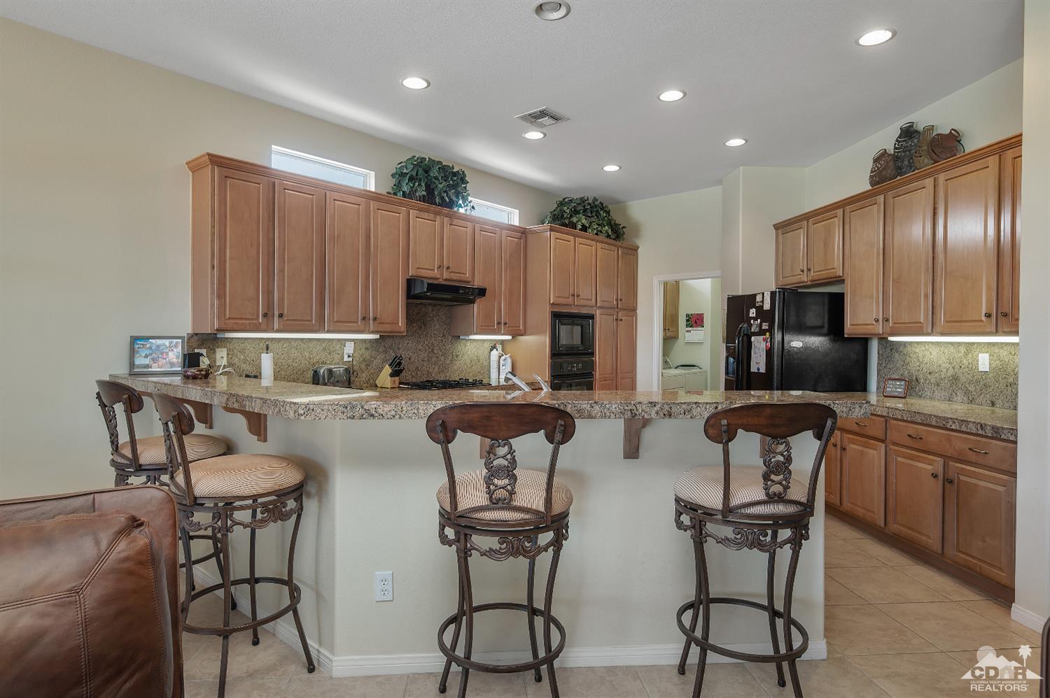 80557 Knightswood Road Indio, CA 92201 - Photo 14 of 30 a kitchen with stainless steel appliances granite countertop a table chairs refrigerator and microwave