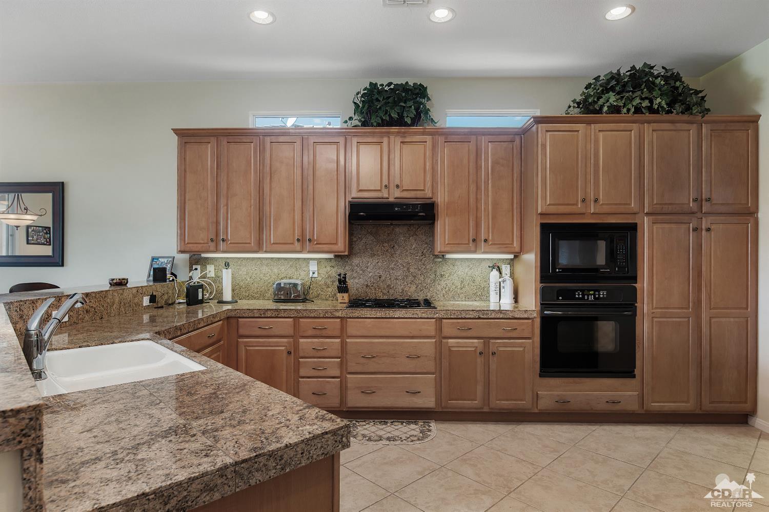 80557 Knightswood Road Indio, CA 92201 - Photo 15 of 30 a kitchen with kitchen island granite countertop wooden cabinets a sink and dishwasher