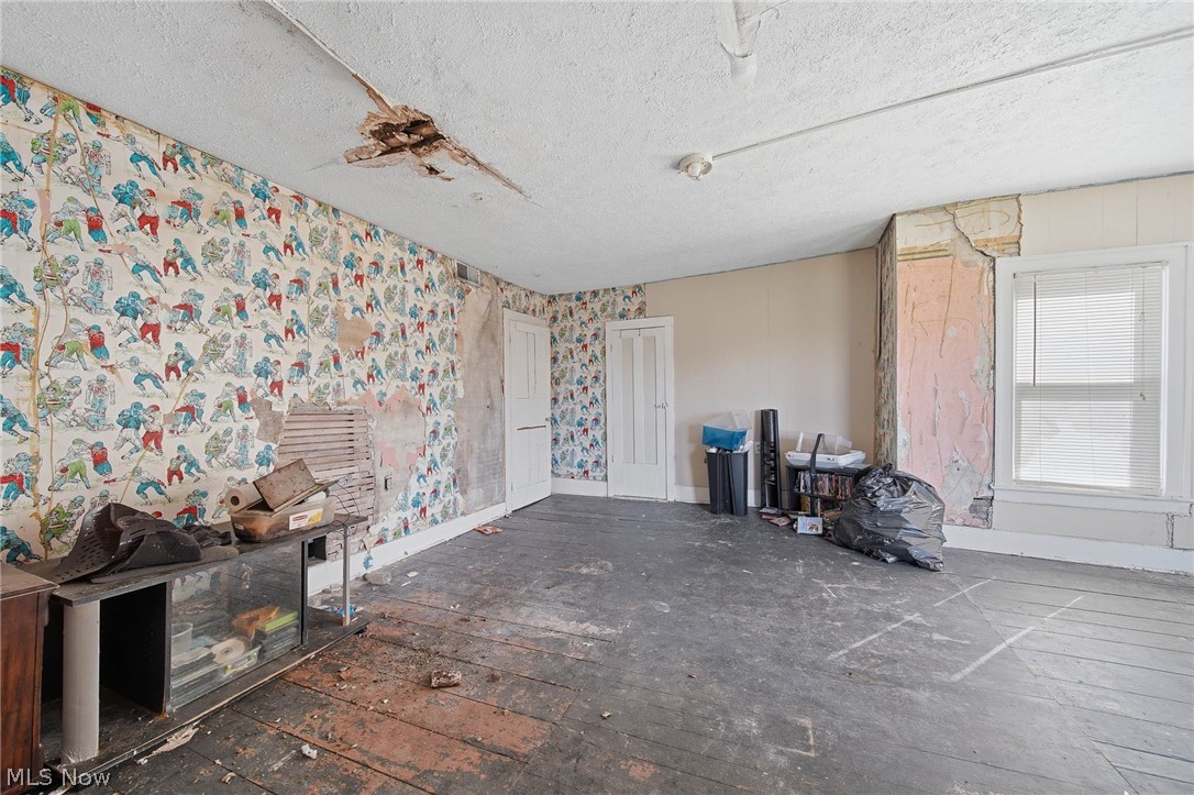 4677 Rock Spring Road Ravenna, OH 44266 - Photo 20 of 35 Unfurnished living room featuring a textured ceiling, dark wood-style flooring, and wallpapered walls