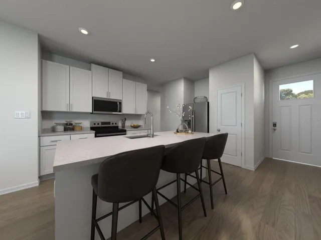 a kitchen with stainless steel appliances a dining table chairs microwave and sink