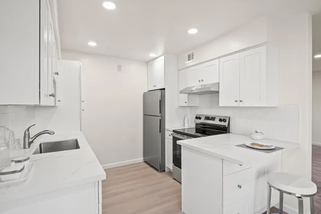a kitchen with a sink a refrigerator and white cabinets