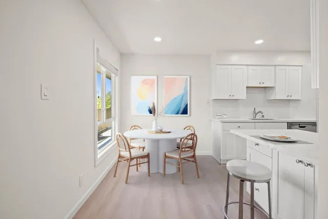 a kitchen with a dining table chairs and white cabinets