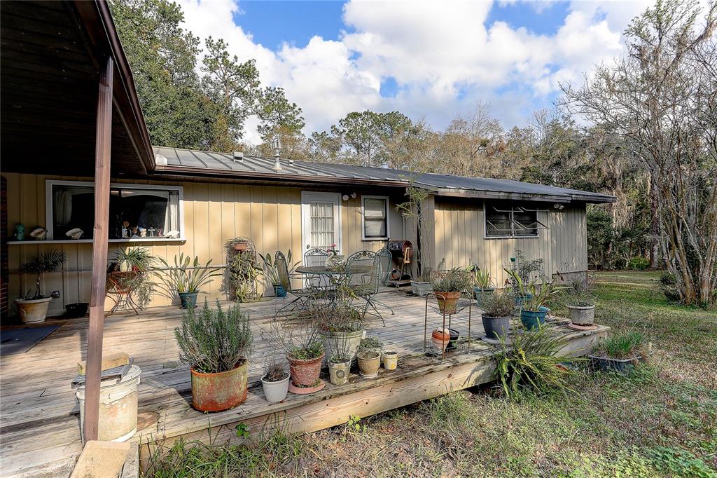 20490 Pinewood Dairy Road Brooksville, FL 34601 - Photo 29 of 52 a view of a patio with table and chairs potted plants with wooden floor