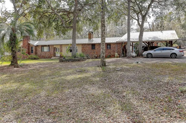 a view of a big house with large tree and a yard