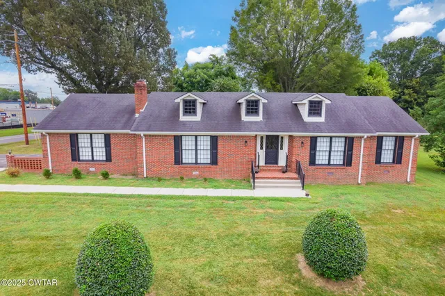 a front view of a house with a garden and trees