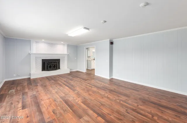 a view of empty room with wooden floor and fireplace