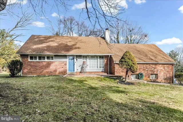 a front view of a house with a garden and trees