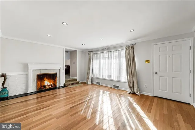 a view of an empty room with wooden floor fireplace and a window