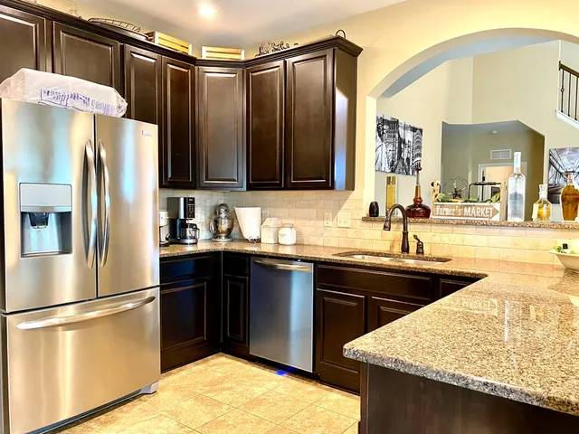 a kitchen with granite countertop a sink stainless steel appliances and cabinets