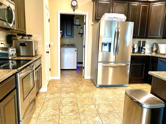 a kitchen with stainless steel appliances granite countertop a refrigerator a stove and a sink