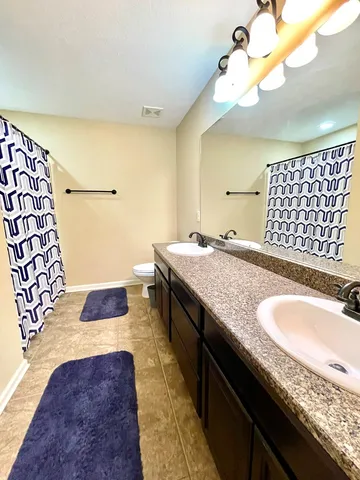 a bathroom with a granite countertop double vanity sink and a mirror