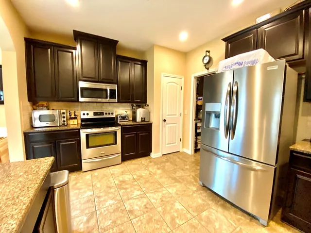 a kitchen with granite countertop a refrigerator and a sink