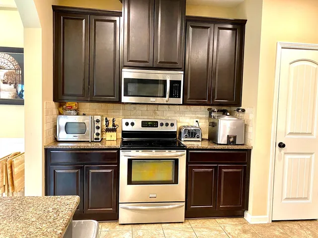 a kitchen with granite countertop wooden cabinets and stainless steel appliances